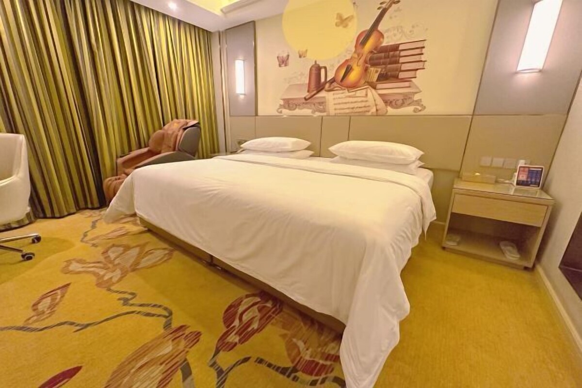 A hotel room with a bed, a nightstand, a chair, and a wall with a mural.