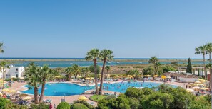 A pool area with multiple pools, palm trees, and a view of the sea. - Casa da Ria - Beautiful view to the sea and Ria Formosa in Algarve (Tavira)