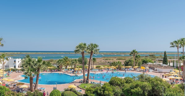A pool area with multiple pools, palm trees, and a view of the sea. - Casa da Ria - Beautiful view to the sea and Ria Formosa in Algarve (Tavira)