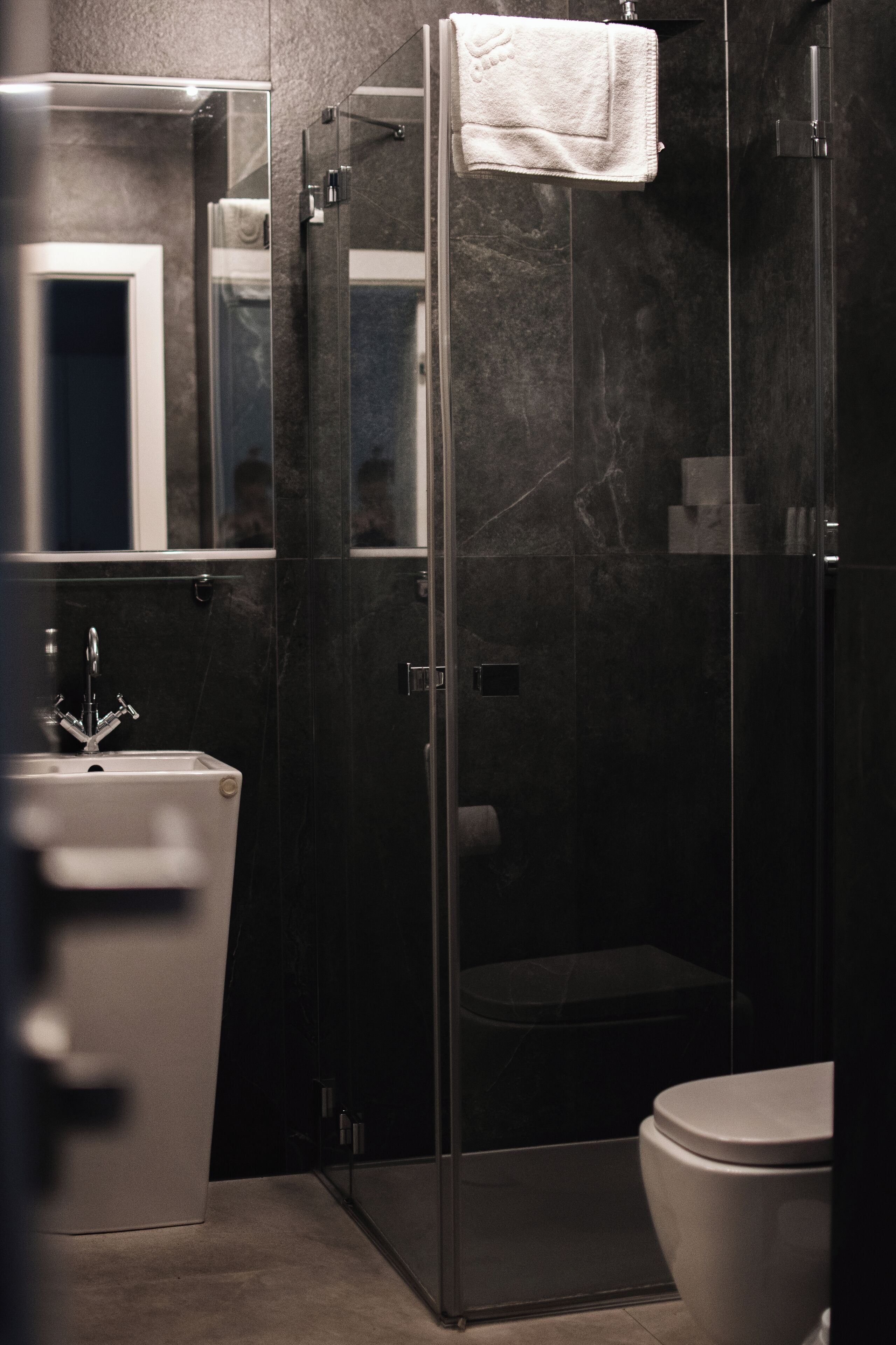 Un baño moderno con cabina de ducha de vidrio, un lavabo blanco y un inodoro.