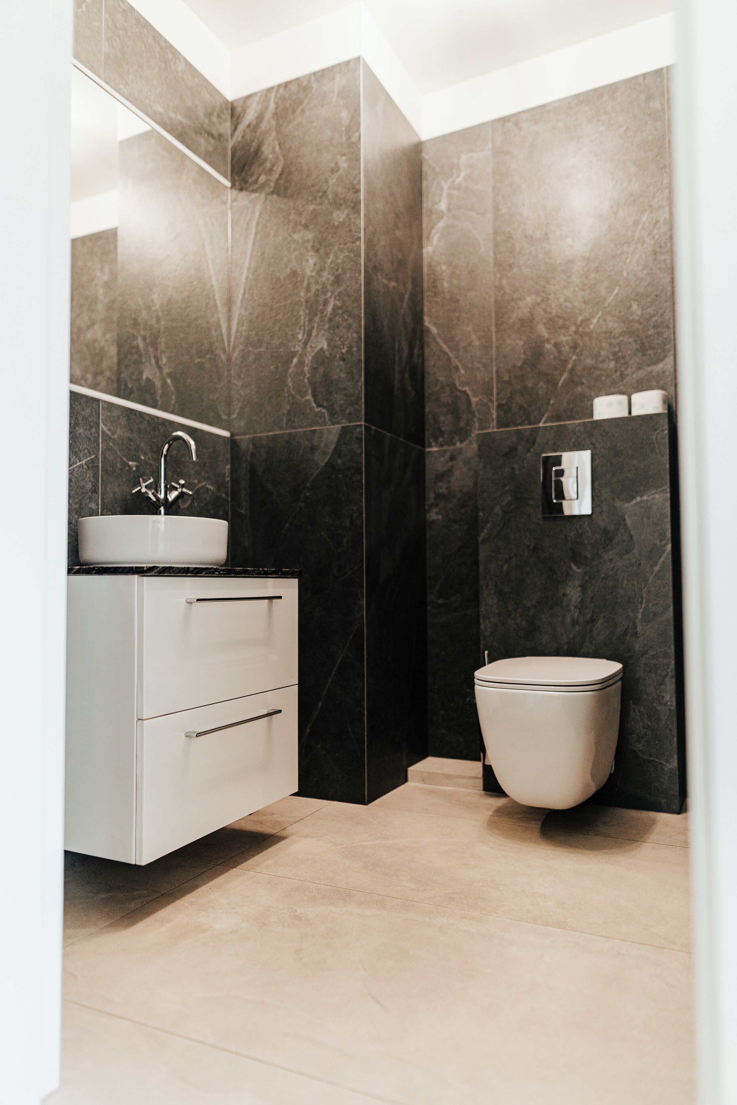 Une salle de bain moderne avec un meuble-lavabo blanc, un évier et des toilettes.
