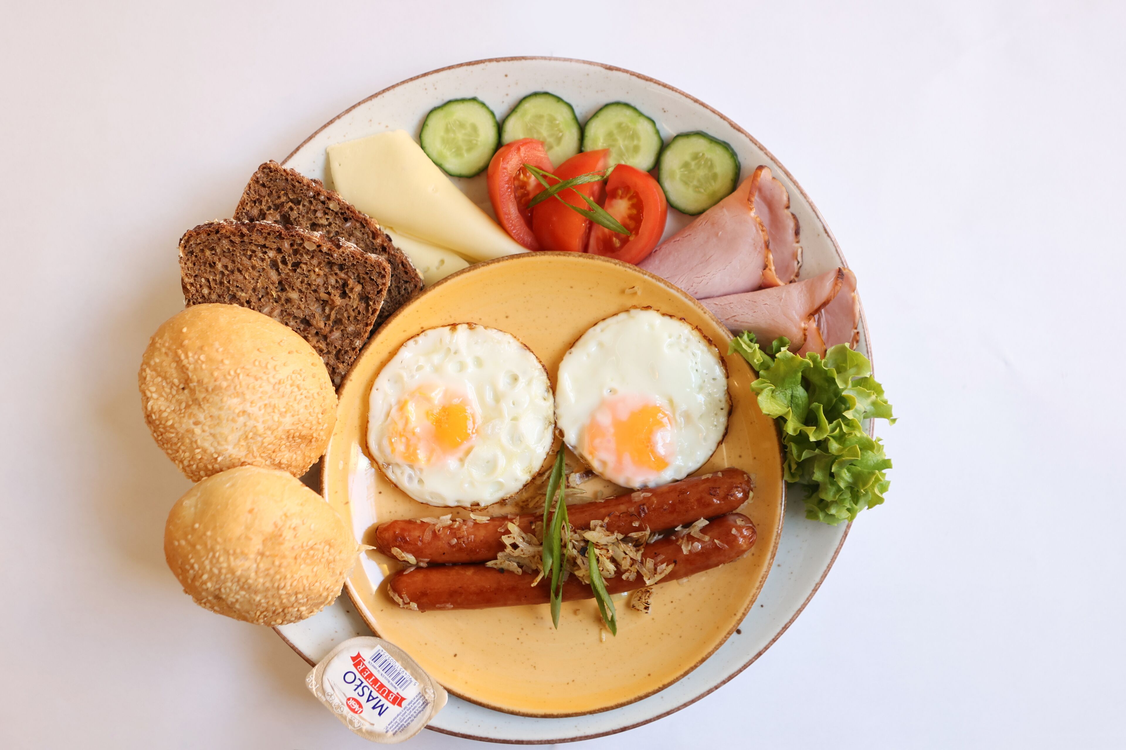 A plate with various breakfast items including eggs, sausages, cheese, and vegetables.