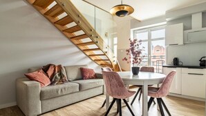 A modern kitchen with a wooden staircase, a dining table with chairs, and a sofa with cushions. - Baltic Gdansk Old Town (Gdansk)