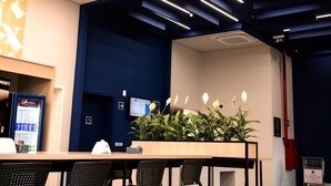 A conference room with a long table, black chairs, a plant, and a vending machine. - Ibis Budget Capao Bonito (Capao Bonito)