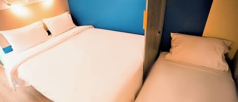 Una habitación de hotel con una cama, una mesita de noche y una lámpara de pared.