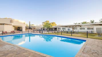 Una piscina al aire libre, sillones reclinables de piscina