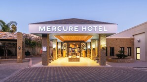 The exterior of the Mercure Hotel with a clear entrance, a well-lit lobby, and a brick facade.