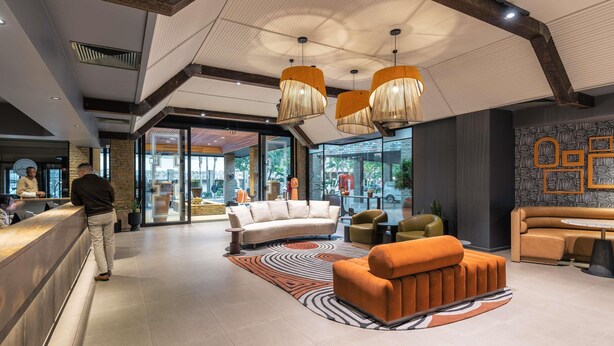 A modern lobby with a reception desk, seating area, and large windows.