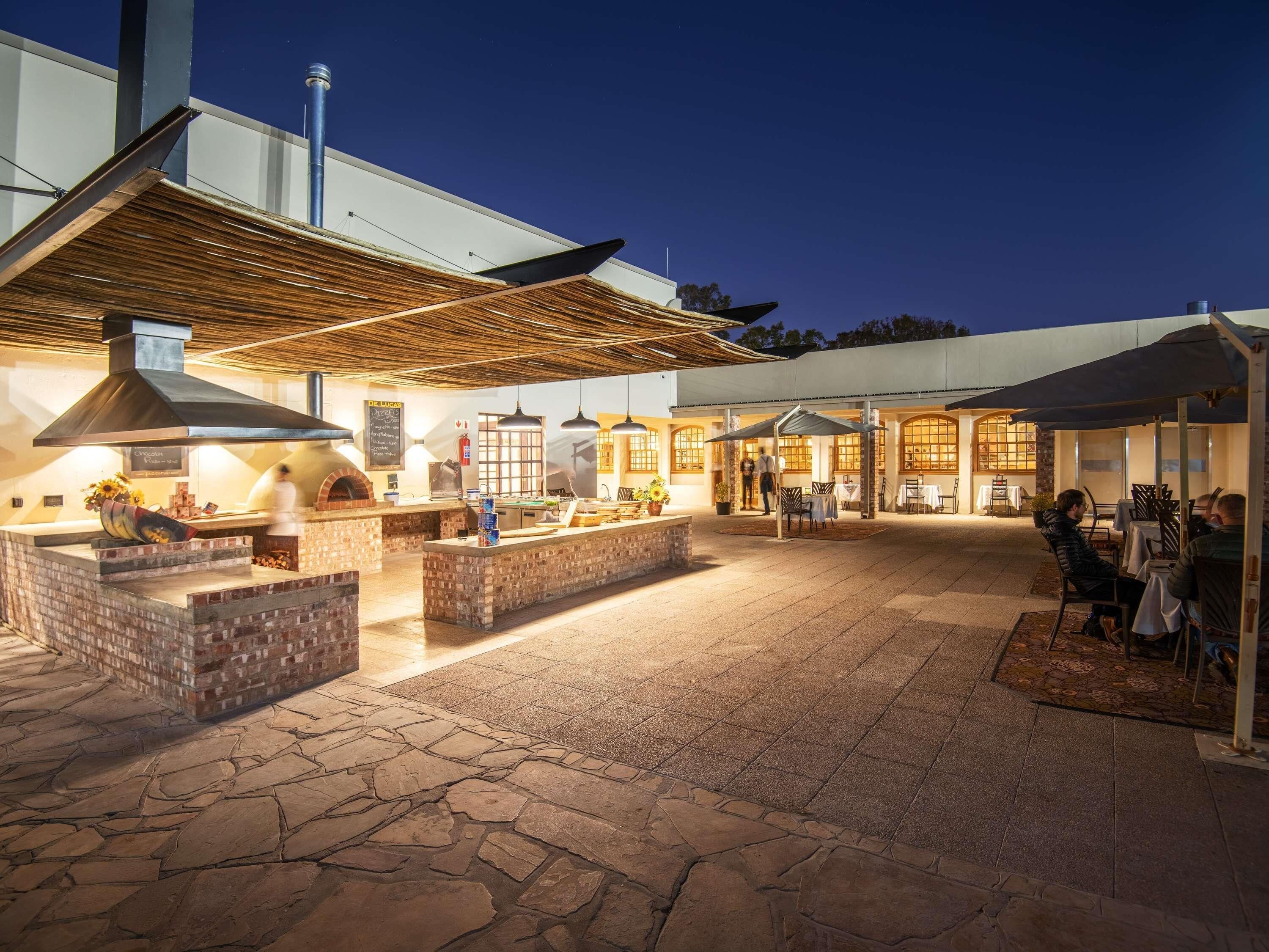 An outdoor patio area with a brick fireplace, outdoor seating, and a covered dining area.