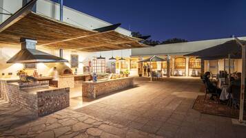 An outdoor patio area with a brick fireplace, outdoor seating, and a covered dining area.