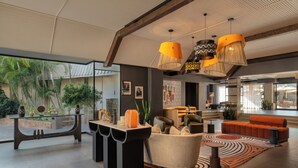 A spacious lobby with a modern design, featuring a seating area with sofas and a coffee table, a reception desk, and a view of the outdoor garden.
