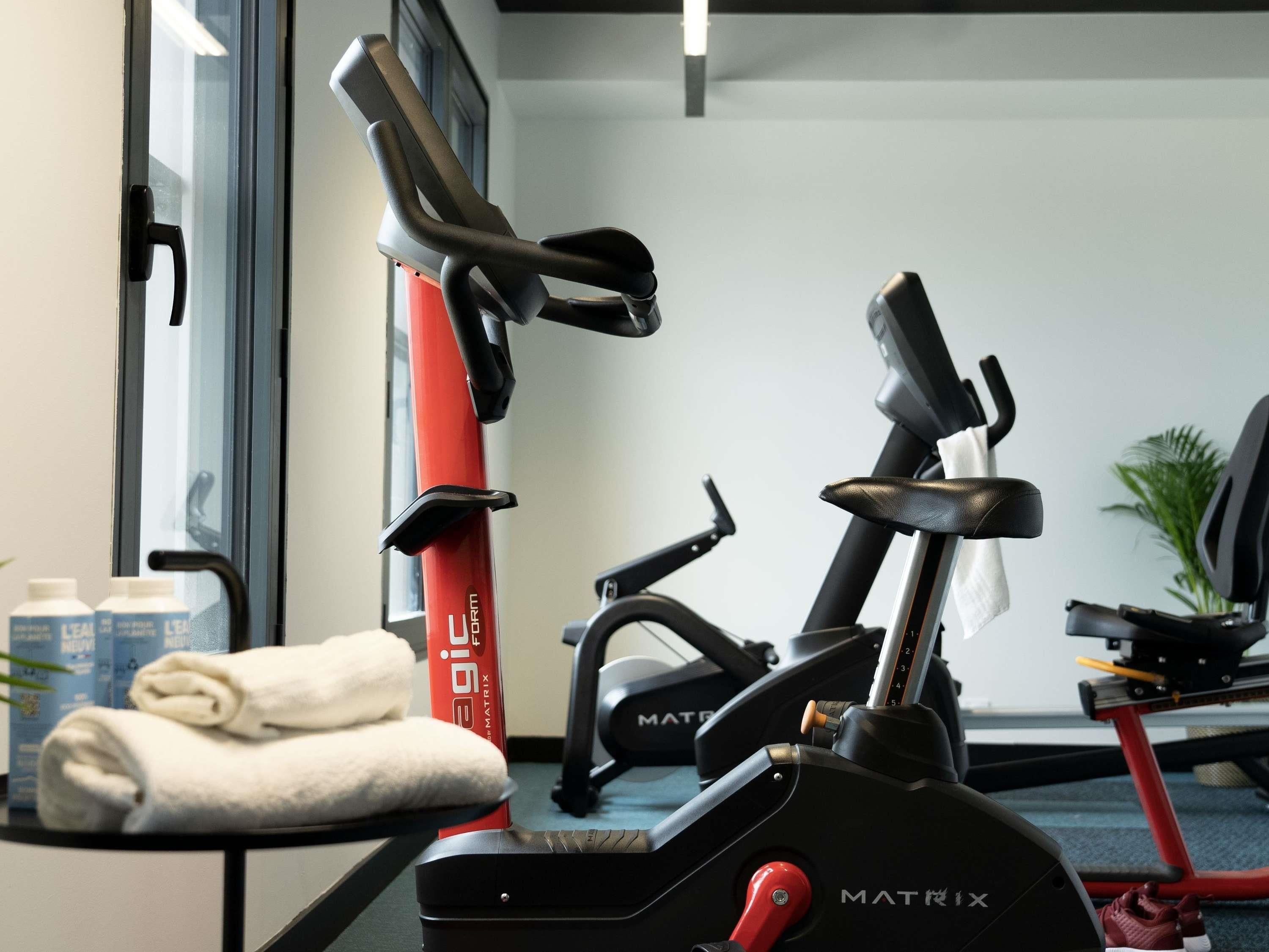 A gym with exercise equipment, a towel, and a water bottle.
