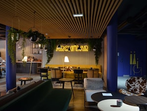 A modern interior with a neon sign reading "ARCHITALAR," featuring a wooden ceiling, hanging plants, and a seating area with tables and chairs. - Ibis Styles Dreux Centre Gare (Dreux)