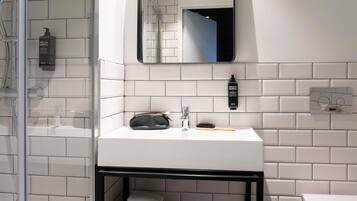 Une salle de bain moderne avec un lavabo blanc, un miroir et un sac à main noir posé sur le comptoir.
