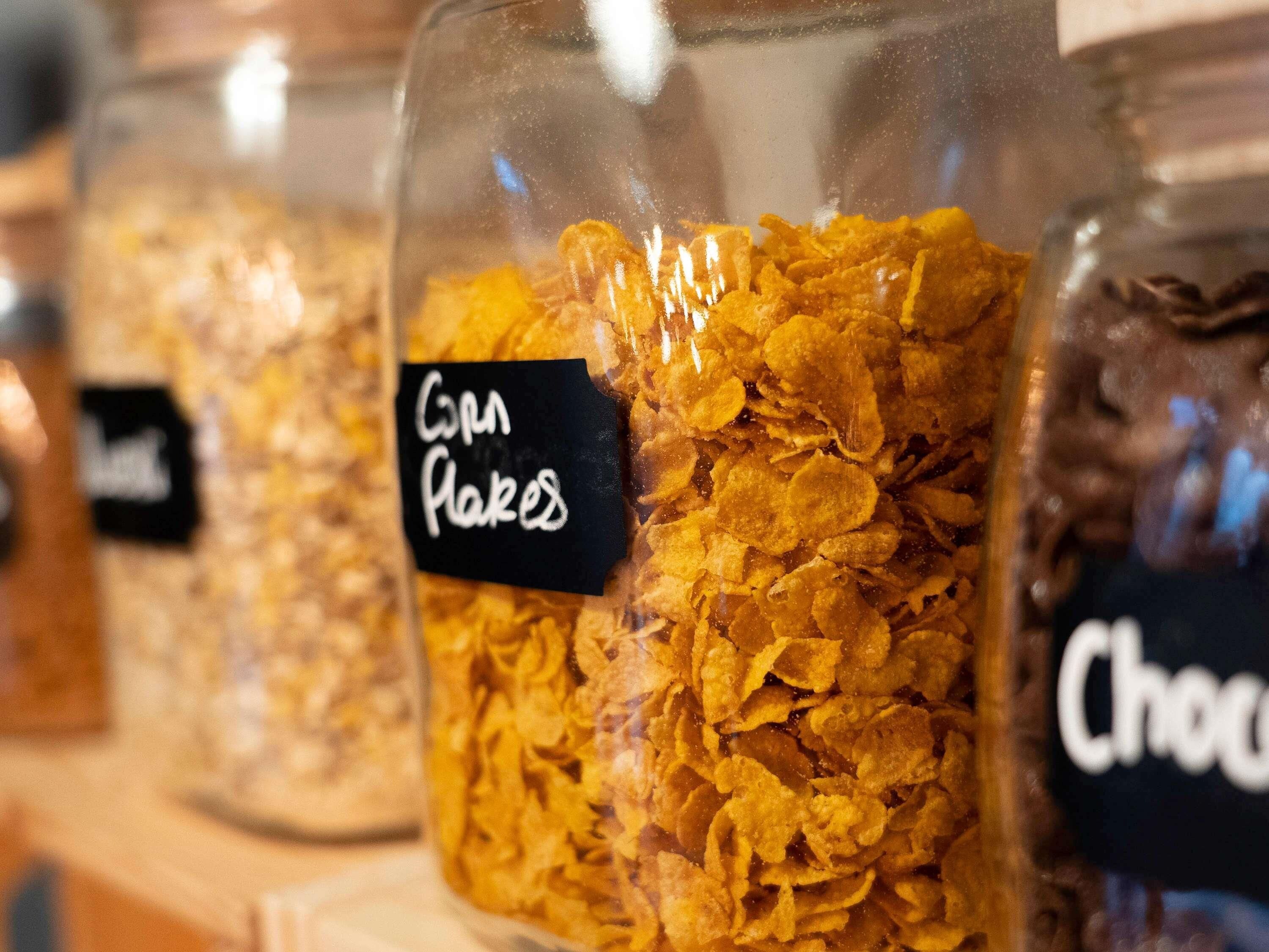 A shelf with jars labeled "Corn Flakes" and "Chocolate."