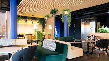 A modern lounge area with seating, hanging plants, and a neon sign.