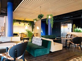 Un espacio lounge moderno con asientos, plantas colgantes y un letrero de neón.