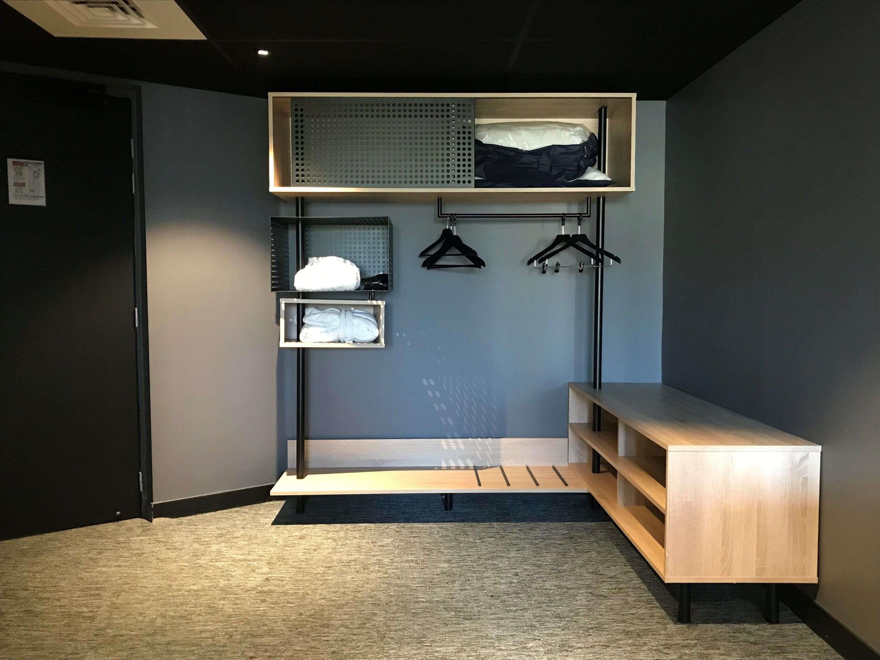 A modern room with a built-in bench, a wall-mounted storage unit, and a hanging rack for clothes.