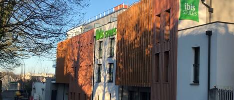 A modern building with a wooden facade and a green sign reading "ibis Styles".