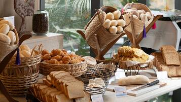 Mostrador de panadería con panes, pasteles y una decoración de gallo.