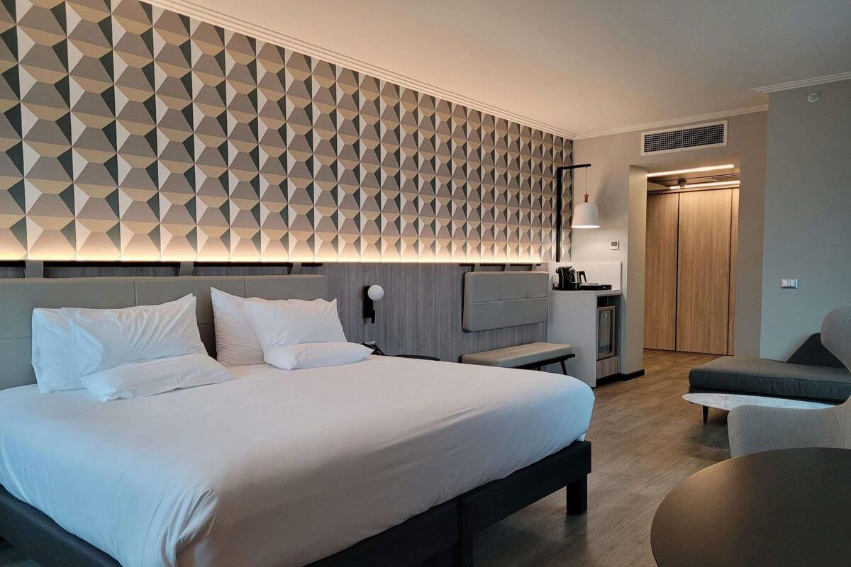 Una habitación de hotel moderna con una cama grande, un escritorio, una silla y una mesa redonda.