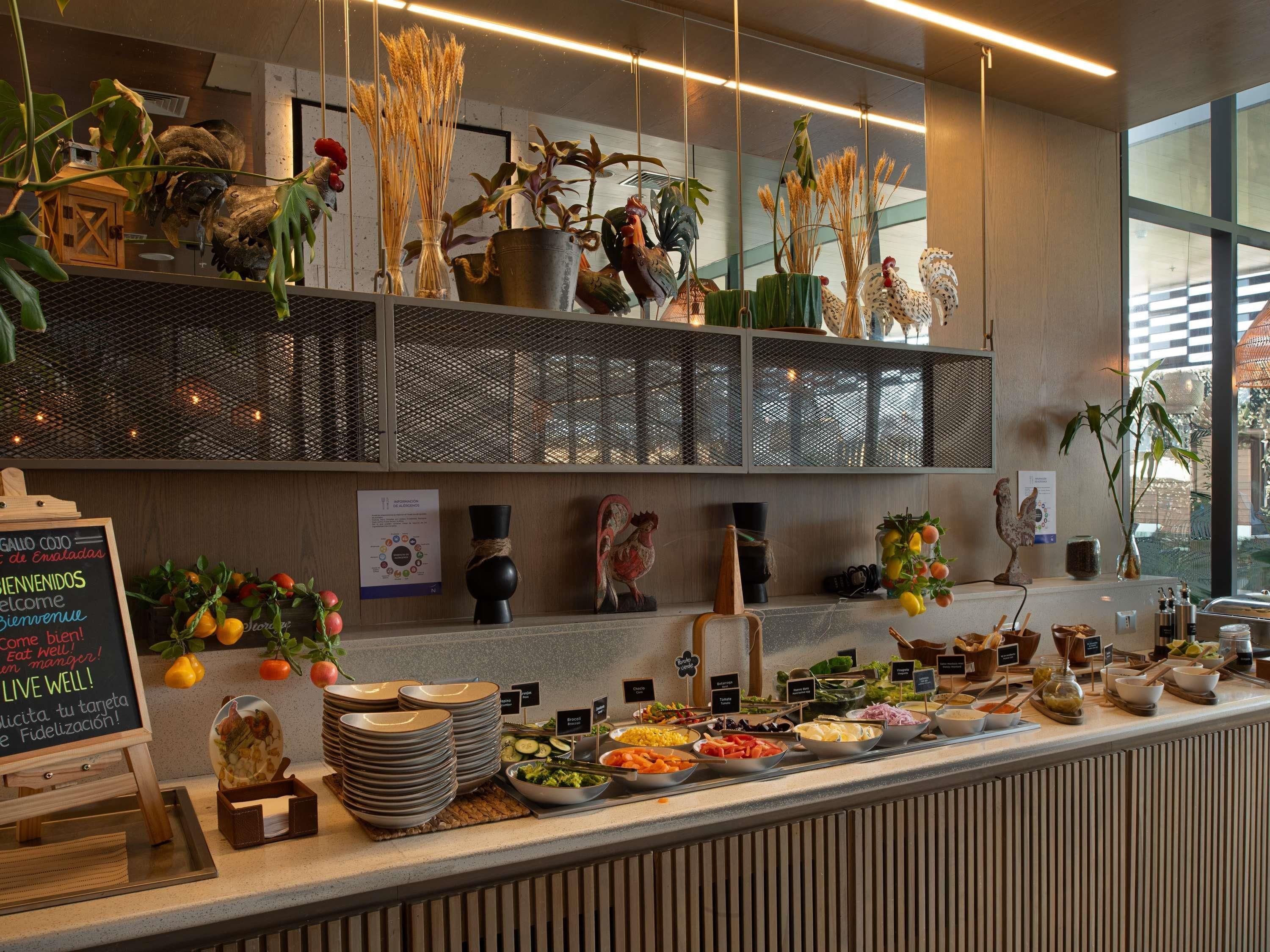 A buffet setup with various food items, a chalkboard sign, and decorative plants.