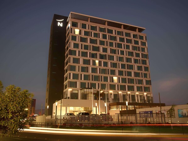 Un hotel de varios pisos con fachada moderna, amplias ventanas y un llamativo logotipo 'N' en la lateral.