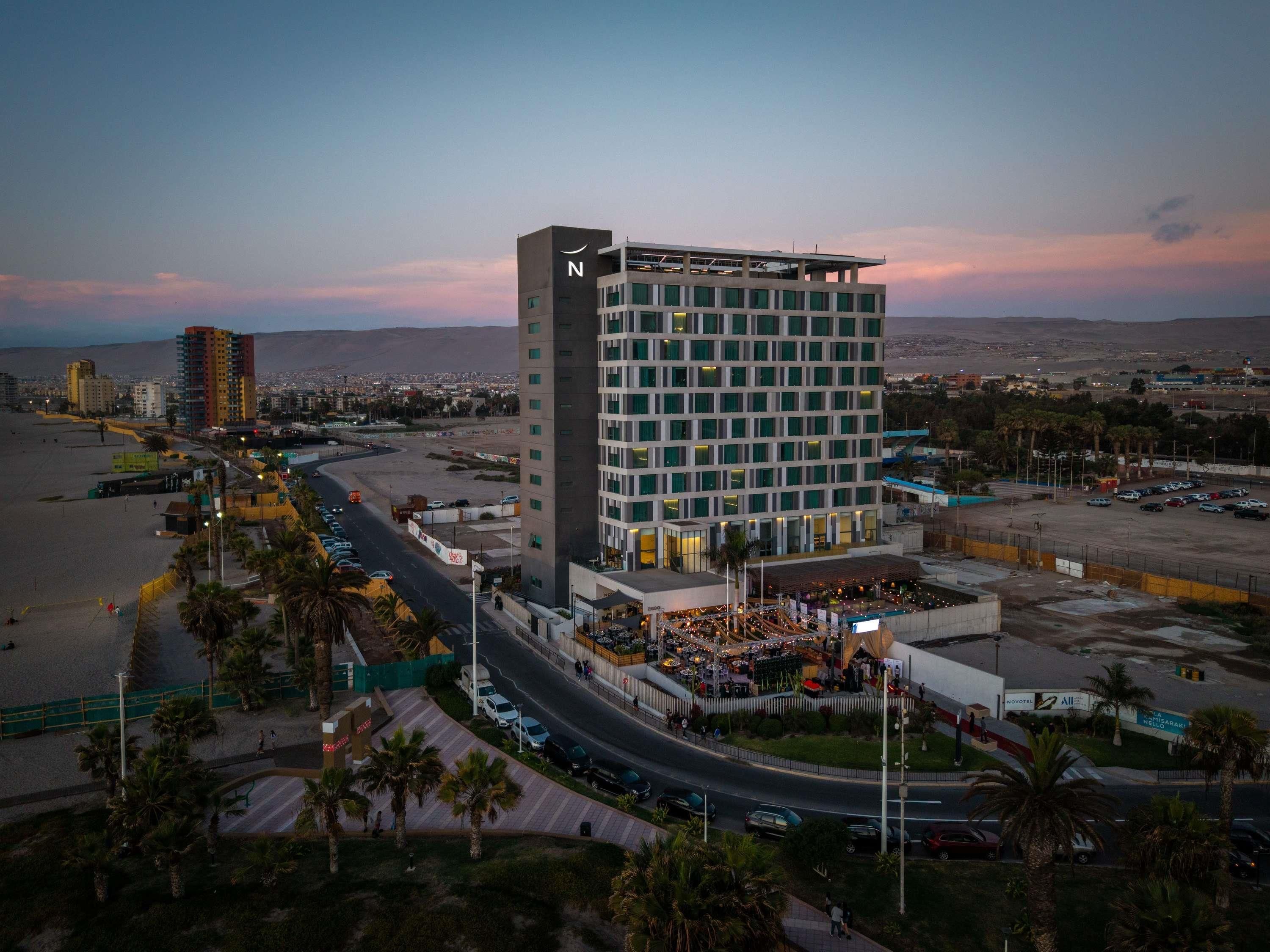 Un hôtel de grande hauteur au design moderne, caractérisé par un grand « N » sur sa façade, situé près d’une plage et offrant un parking ainsi qu’une vue sur le paysage urbain.
