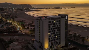A hotel with a modern design, located near a beach with a view of the ocean.