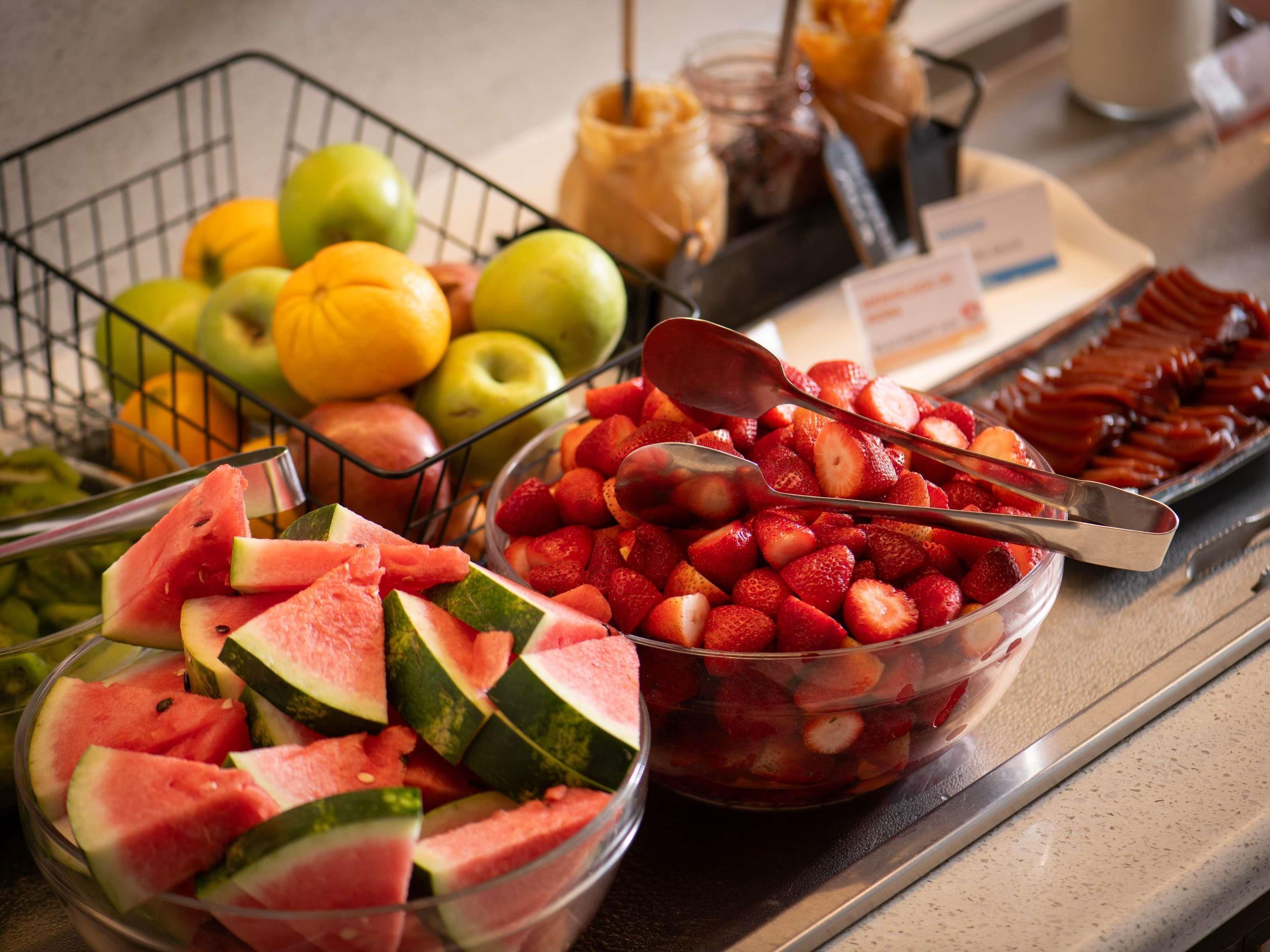 Un buffet proposant une variété de fruits, notamment des pastèques, des fraises et des pommes.