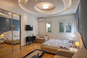 Une chambre moderne avec un grand lit, un canapé, une télévision et un miroir.