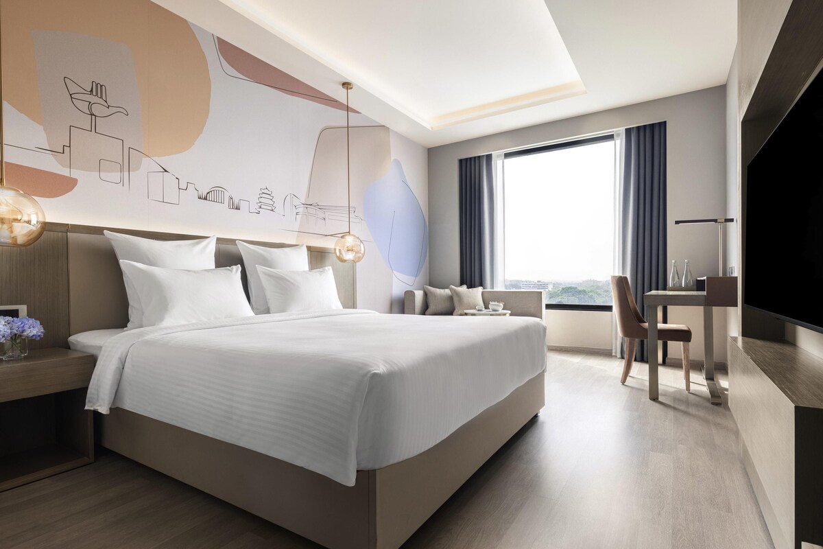 Une chambre d’hôtel moderne équipée d’un grand lit, d’un bureau, d’une chaise et d’une télévision.