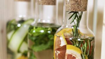 Tres botellas de vidrio con tapones de corcho, llenas de agua, con rodajas de limón, romero y un trozo de carne.