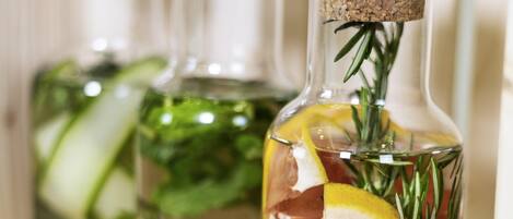 Tres botellas de vidrio con tapones de corcho, llenas de agua, con rodajas de limón, romero y un trozo de carne.