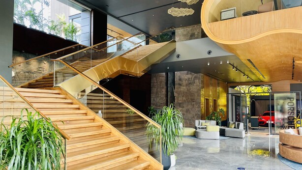 Ein modernes Interieur mit einer Holztreppe, Sitzbereichen und einem Porsche-Showroom.