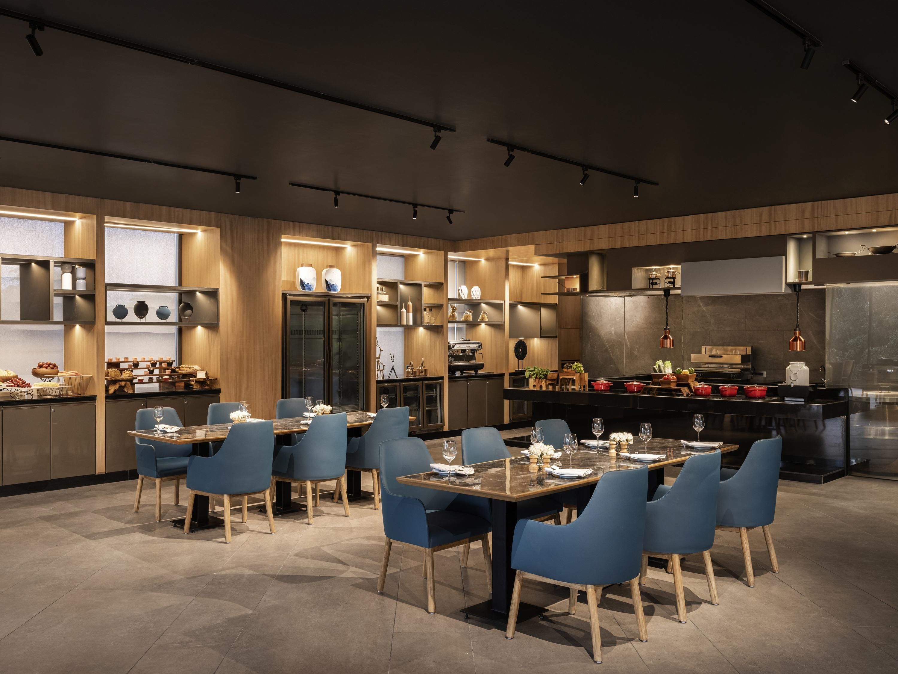 Una cocina moderna con electrodomésticos integrados, armarios de madera y una zona de comedor con sillas azules y una mesa de mármol.
