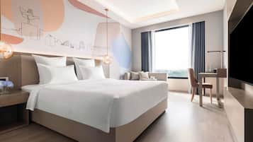 Una habitación de hotel moderna con una cama grande, un escritorio, una silla y un televisor.