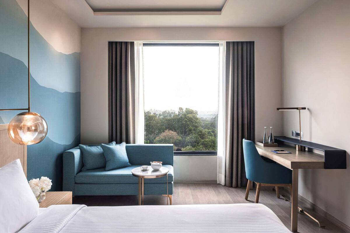 Una habitación de hotel moderna con una cama, un sofá, un escritorio y vistas al exterior.