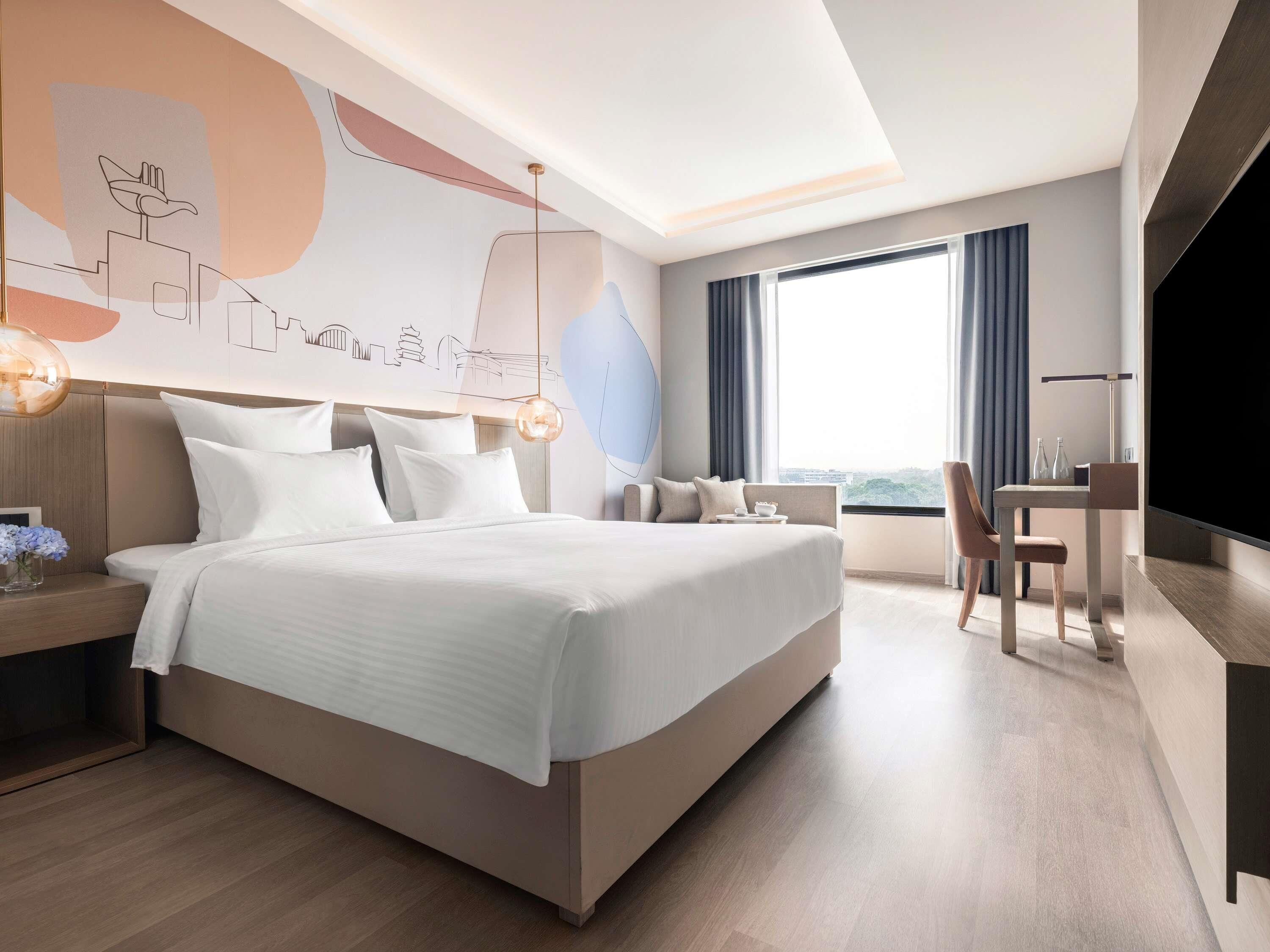 Una habitación de hotel moderna con una cama grande, un escritorio, una silla y un televisor.