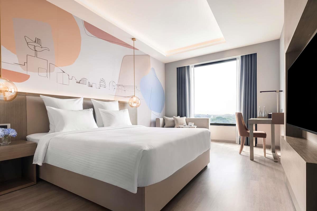 Una habitación de hotel moderna con una cama grande, un escritorio, una silla y un televisor.