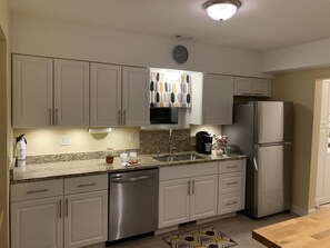 A kitchen with white cabinets, a stainless steel dishwasher, a refrigerator, and a microwave.