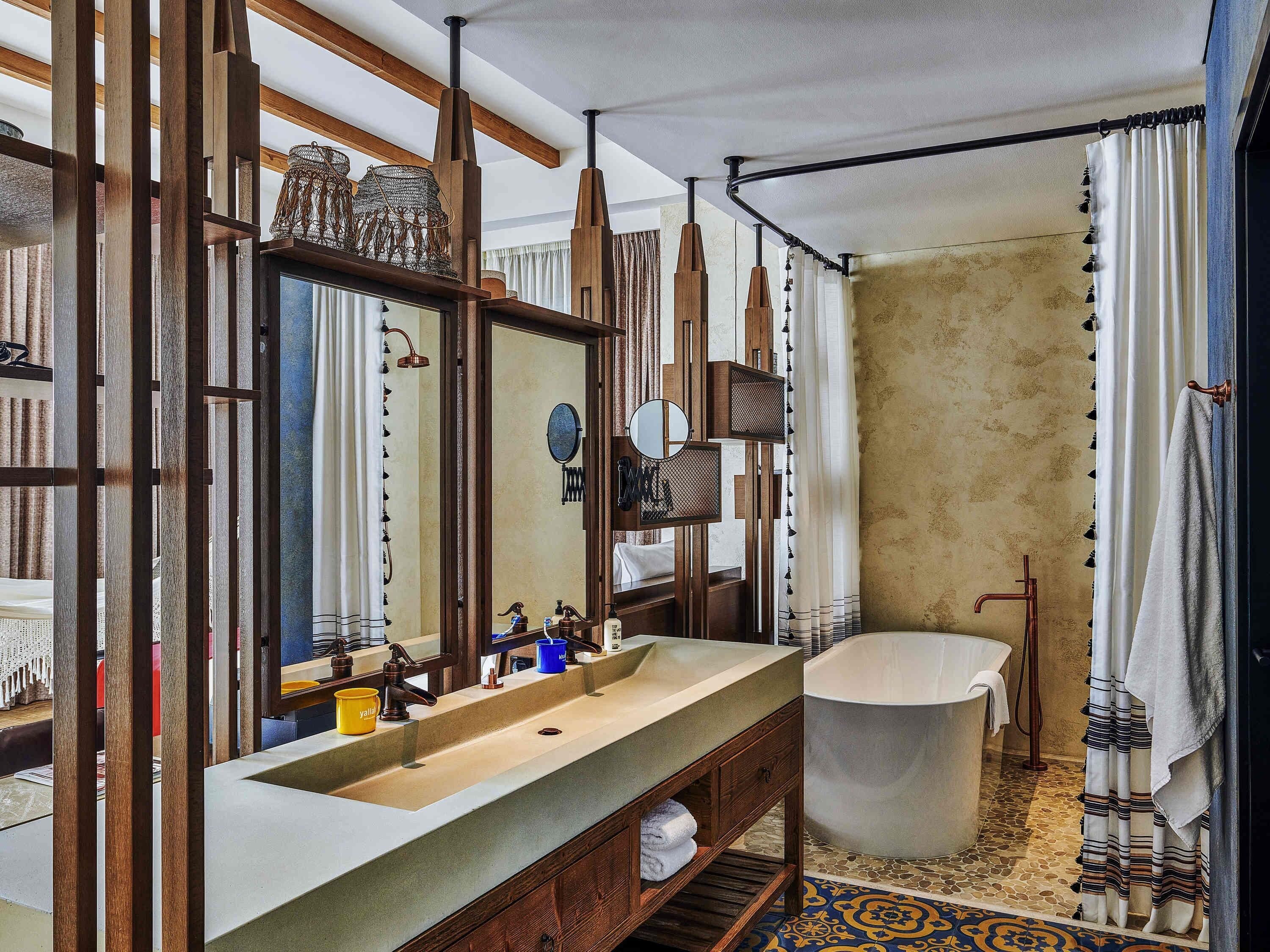 A bathroom with a large bathtub, wooden vanity, and a mirror.