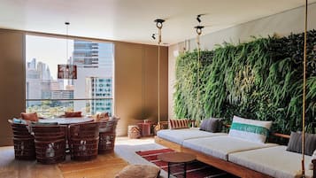 A modern living room with a city view, a hanging plant wall, and a cozy seating area.