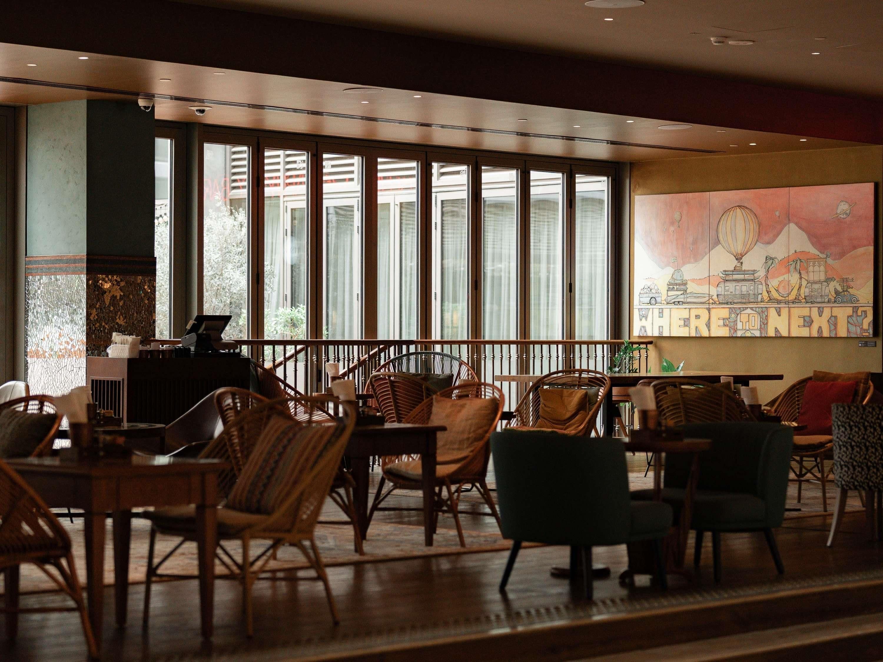 A cafe with wicker chairs, a counter, and large windows.
