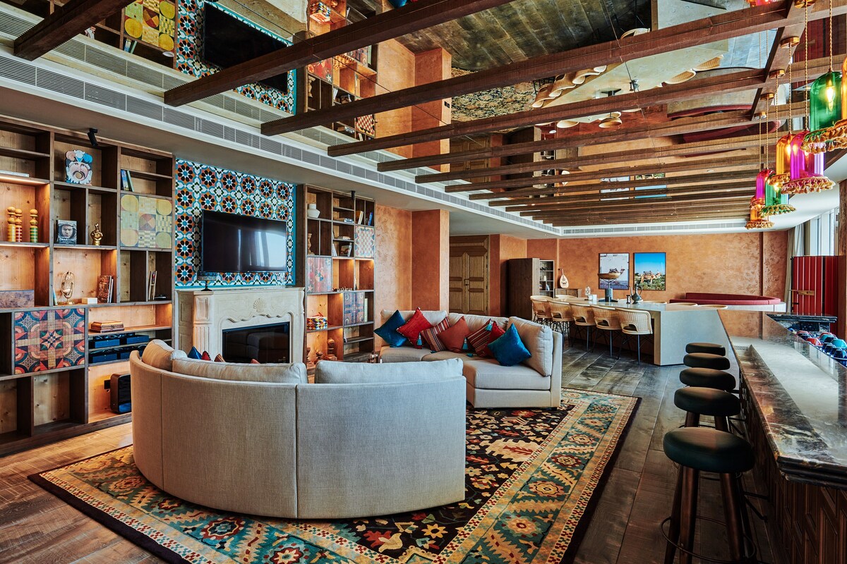 A spacious living area with a large TV, a sofa, and a bar with stools.