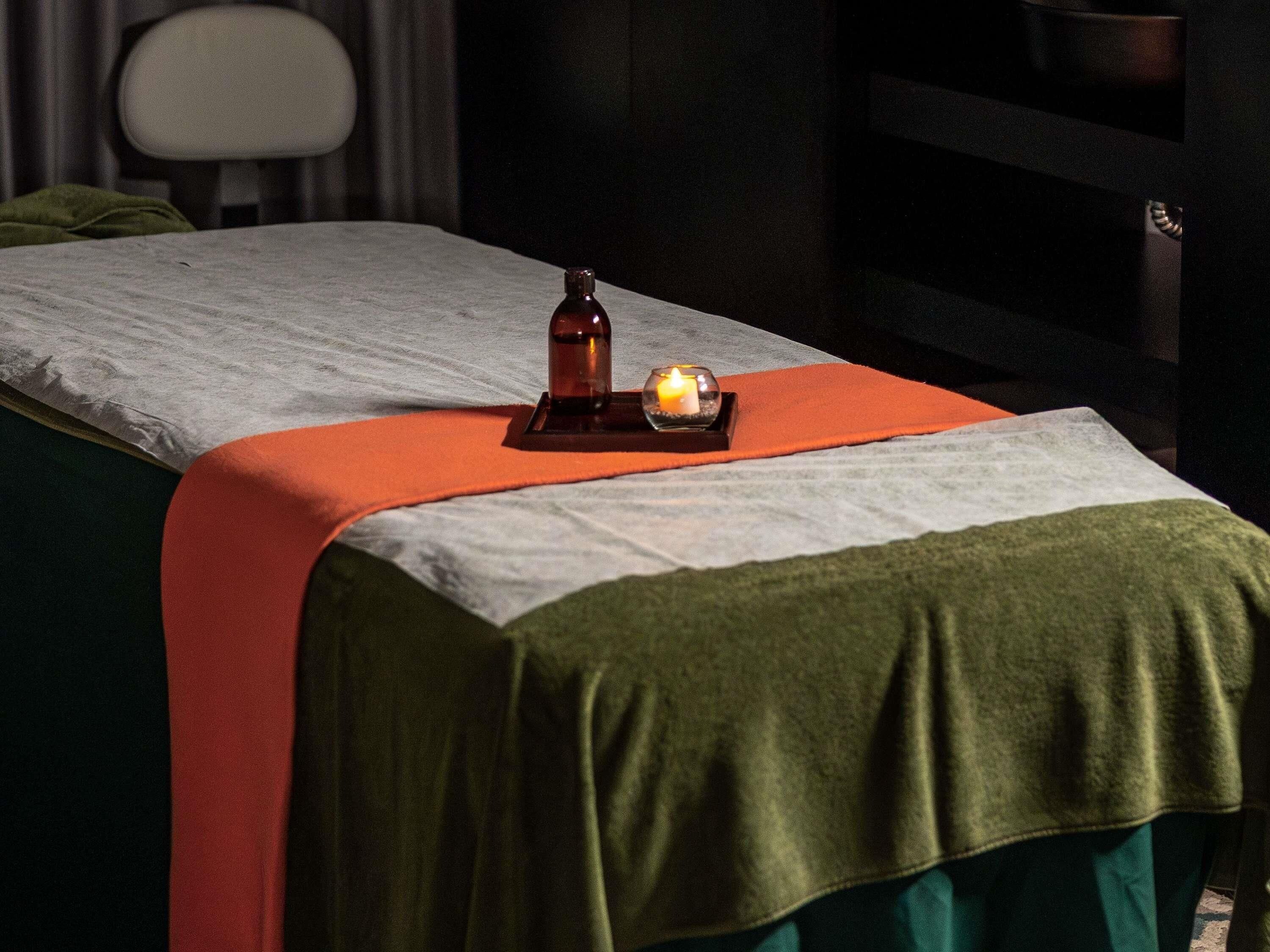 A room with a bed, a small table with a candle, and a chair.