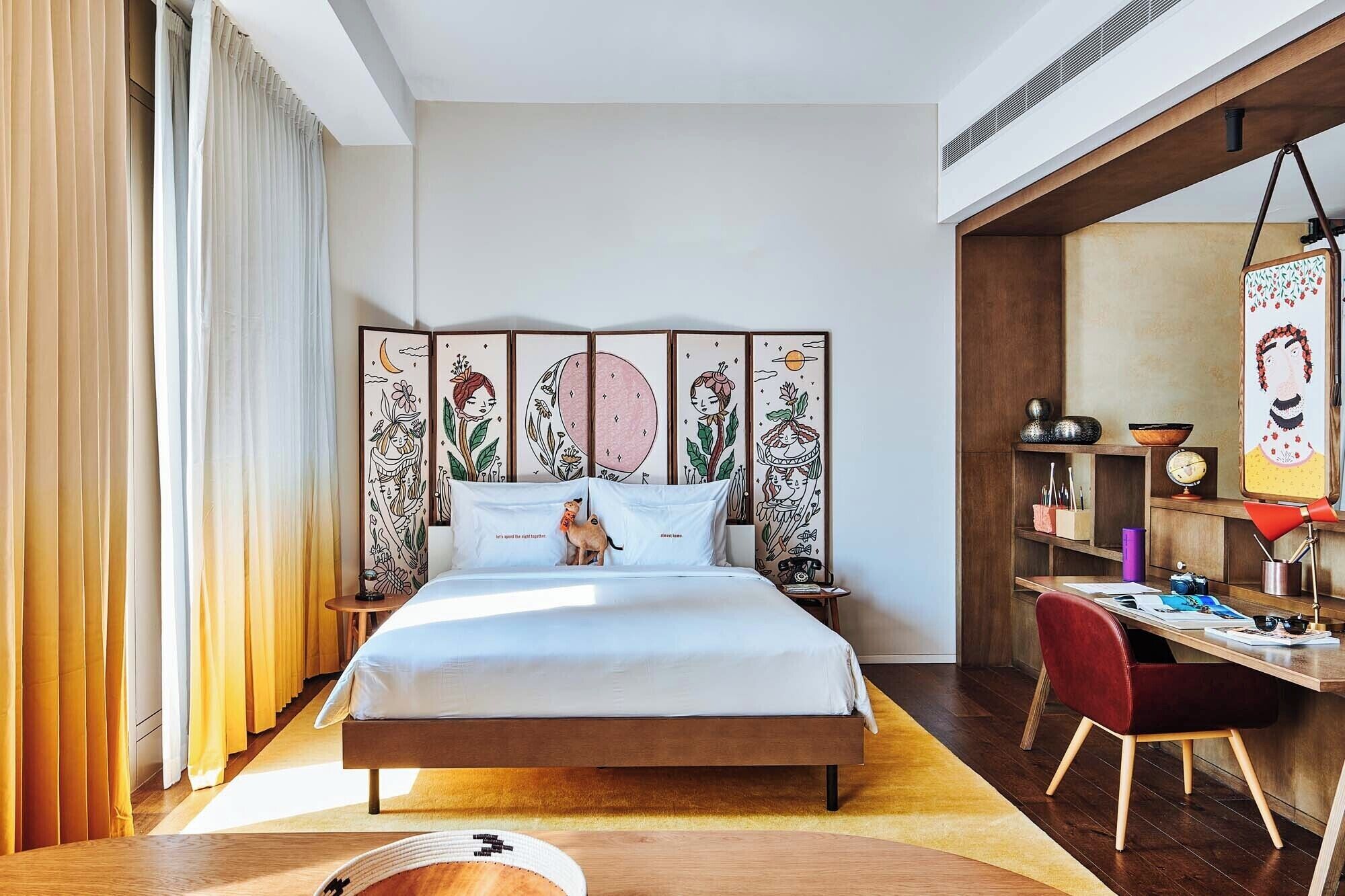 A modern bedroom with a large bed, a desk, and a bookshelf.