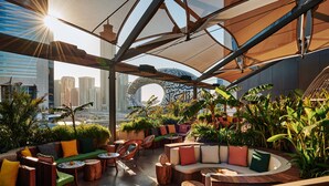 Un espacio al aire libre con muebles de madera, cojines y plantas en macetas.