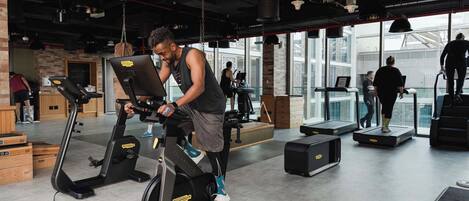 Un gimnasio con bicicletas estáticas, cintas de correr y un ventanal grande.