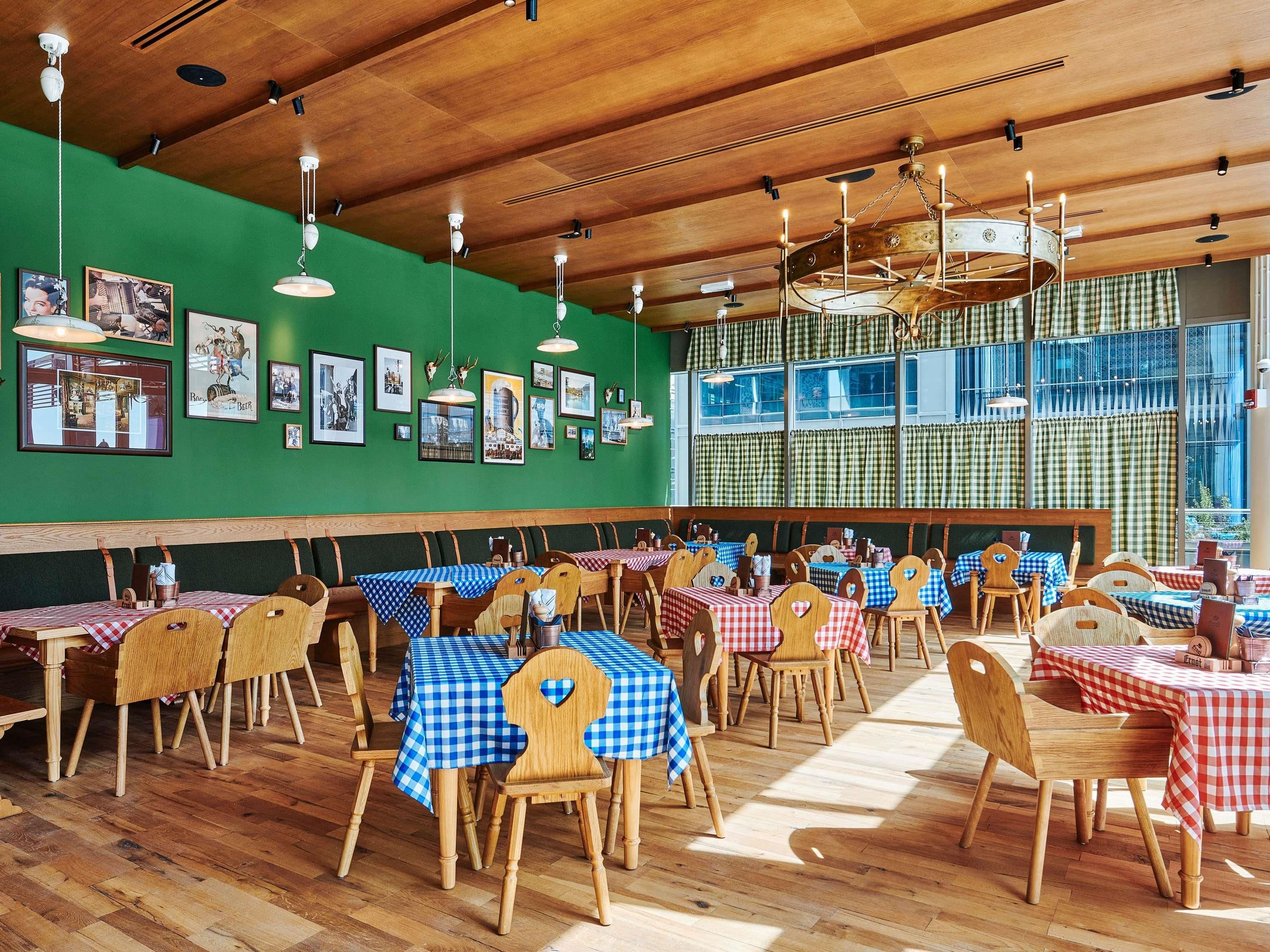 A restaurant with wooden tables and chairs, green walls, and framed pictures.
